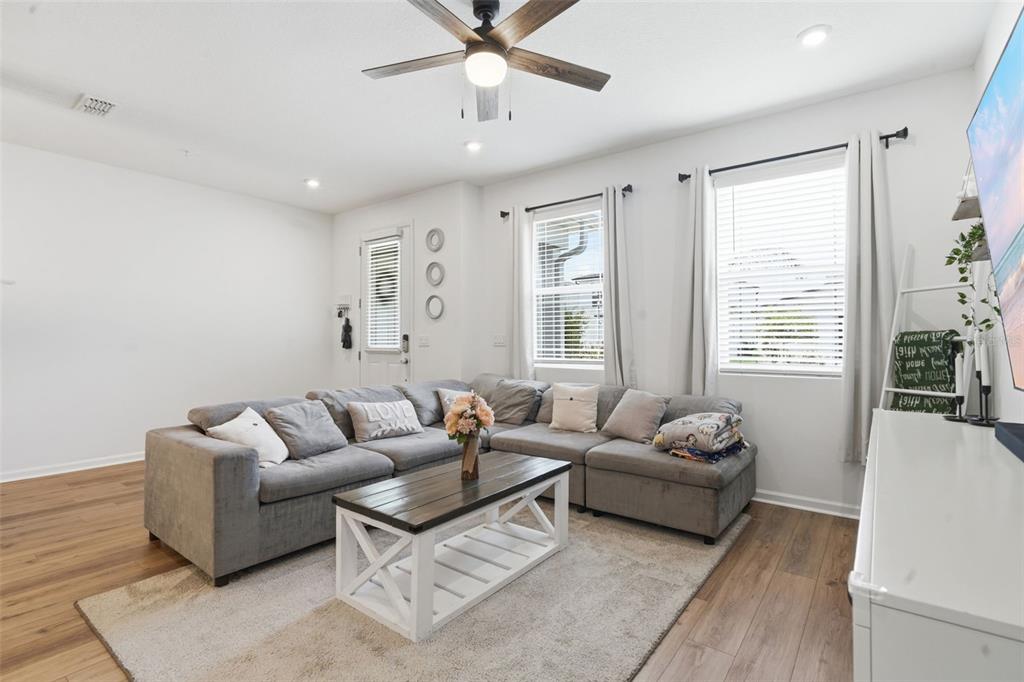 A living room features a gray sectional sofa, a wooden coffee table, and two windows — 11429 SUNSAIL AVENUE, ORLANDO, FL