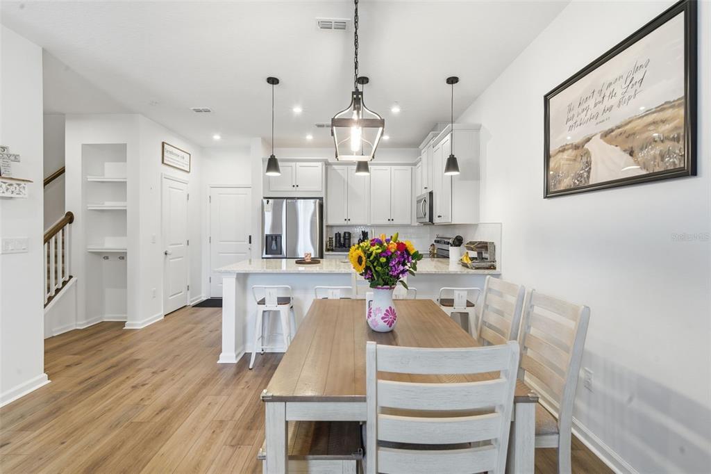 A dining area with a wooden table and chairs sits in front of a white kitchen — 11429 SUNSAIL AVENUE, ORLANDO, FL