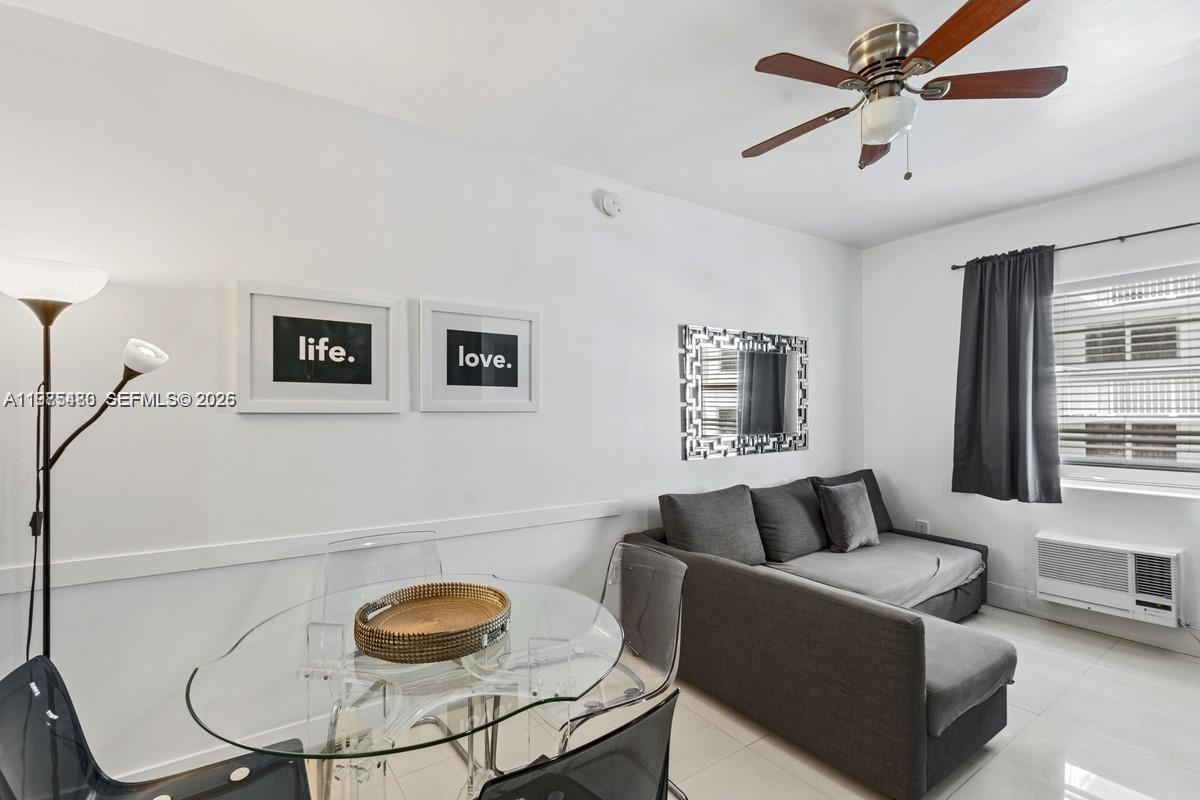 A living room features a glass dining table, a gray sofa, and wall art — 335 Ocean Dr # 310, Miami Beach FL 33139, MIAMI BEACH, FL