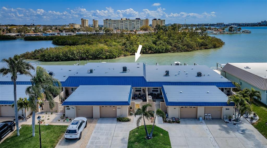 A wooden deck features two chairs and a small table overlooking a boat dock — 476 BOCA CIEGA POINT BOULEVARD S, ST PETERSBURG, FL