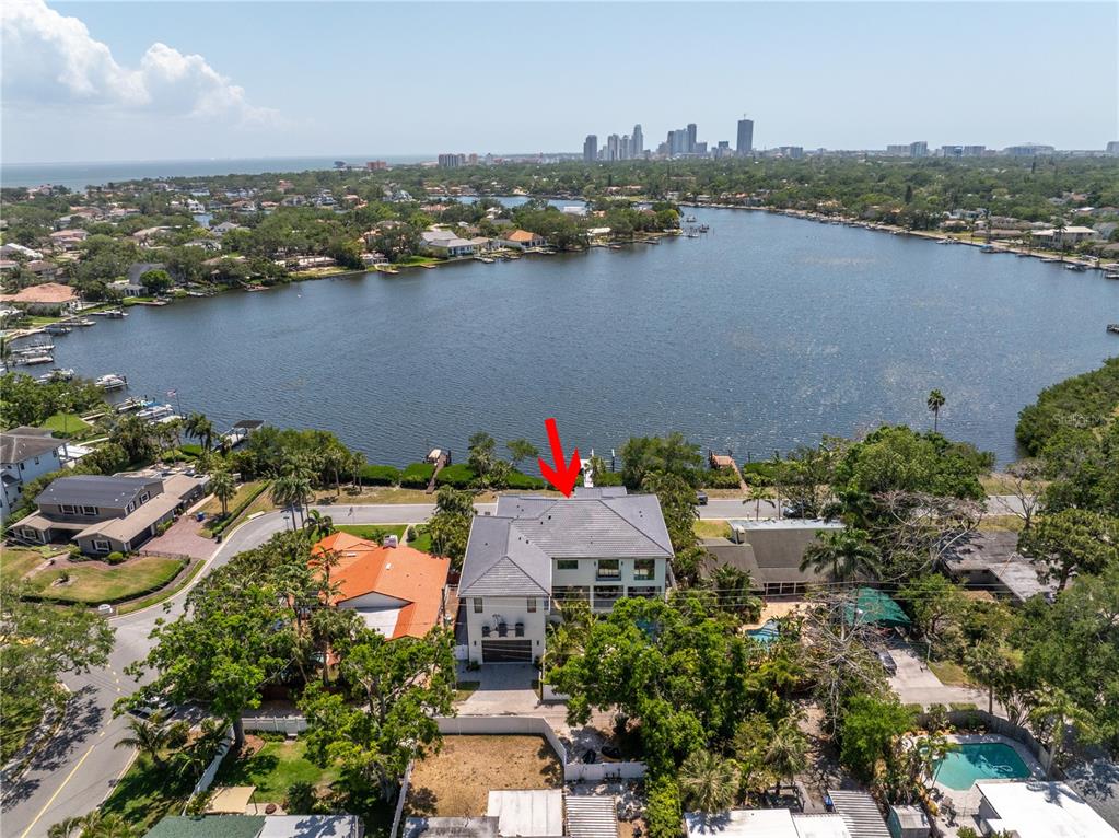 An aerial view shows a multi-story house with a gray roof situated near a lake — 337 COFFEE POT DRIVE NE, ST PETERSBURG, FL