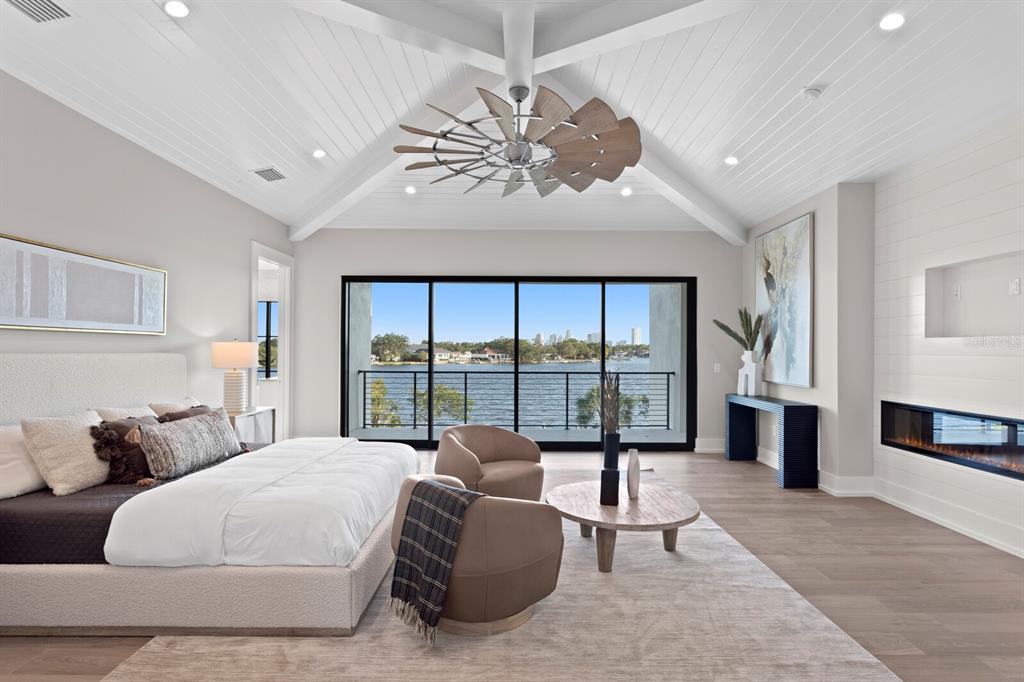 A modern bedroom features a vaulted ceiling, a windmill ceiling fan, and a waterfront balcony — 337 COFFEE POT DRIVE NE, ST PETERSBURG, FL