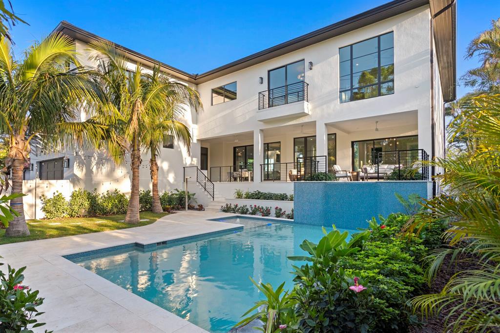 A two-story white house with a swimming pool, patio, and palm trees in the backyard — 337 COFFEE POT DRIVE NE, ST PETERSBURG, FL