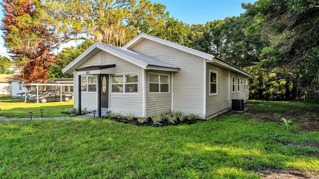 A light-colored, single-story house with a metal roof and a small front porch — 1821 W CHASE STREET, LAKELAND, FL
