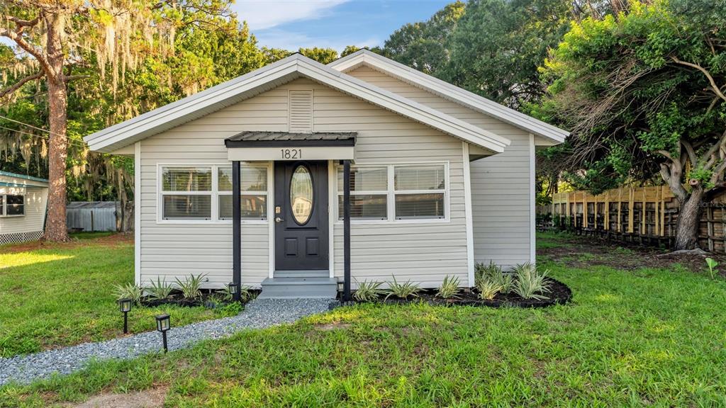 A single-story house with light-colored siding, a dark front door, and a gravel walkway — 1821 W CHASE STREET, LAKELAND, FL