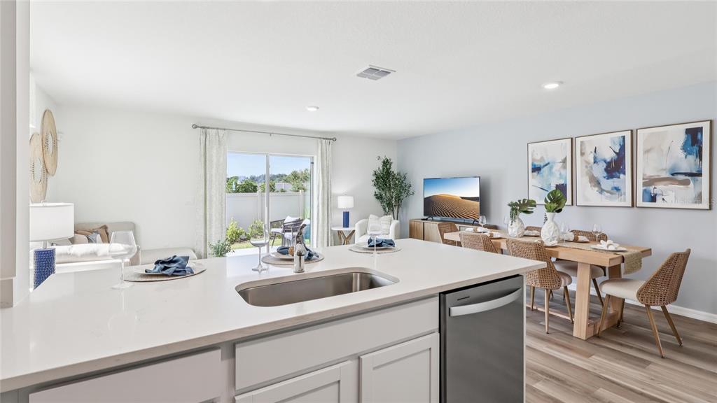 A kitchen island with a sink overlooks an open-concept dining and living area — 11267 NW 167TH TERRACE, ALACHUA, FL