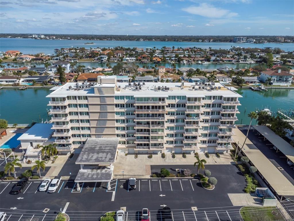 An aerial view shows a multi-story apartment building with a parking lot and waterfront access — 223 ISLAND WAY UNIT 4A, CLEARWATER, FL