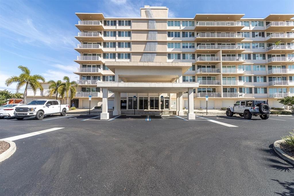 A multi-story apartment building with a covered entrance and parking lot in front — 223 ISLAND WAY UNIT 4A, CLEARWATER, FL