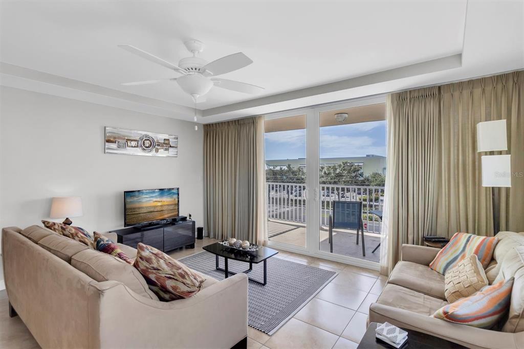 A living room features two beige sofas, a coffee table, and a balcony with outdoor seating — 223 ISLAND WAY UNIT 4A, CLEARWATER, FL