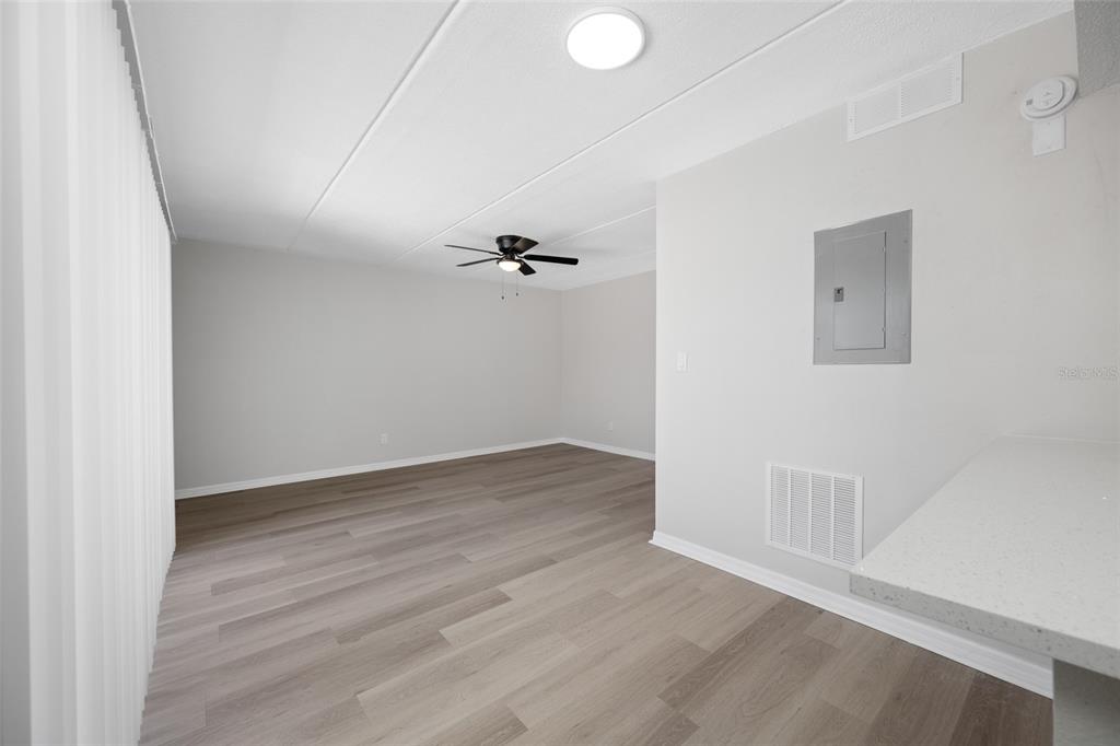 An empty room with light wood-look flooring, a ceiling fan, and a gray electrical panel — 7950 BLIND PASS ROAD UNIT 4, ST PETERSBURG, FL