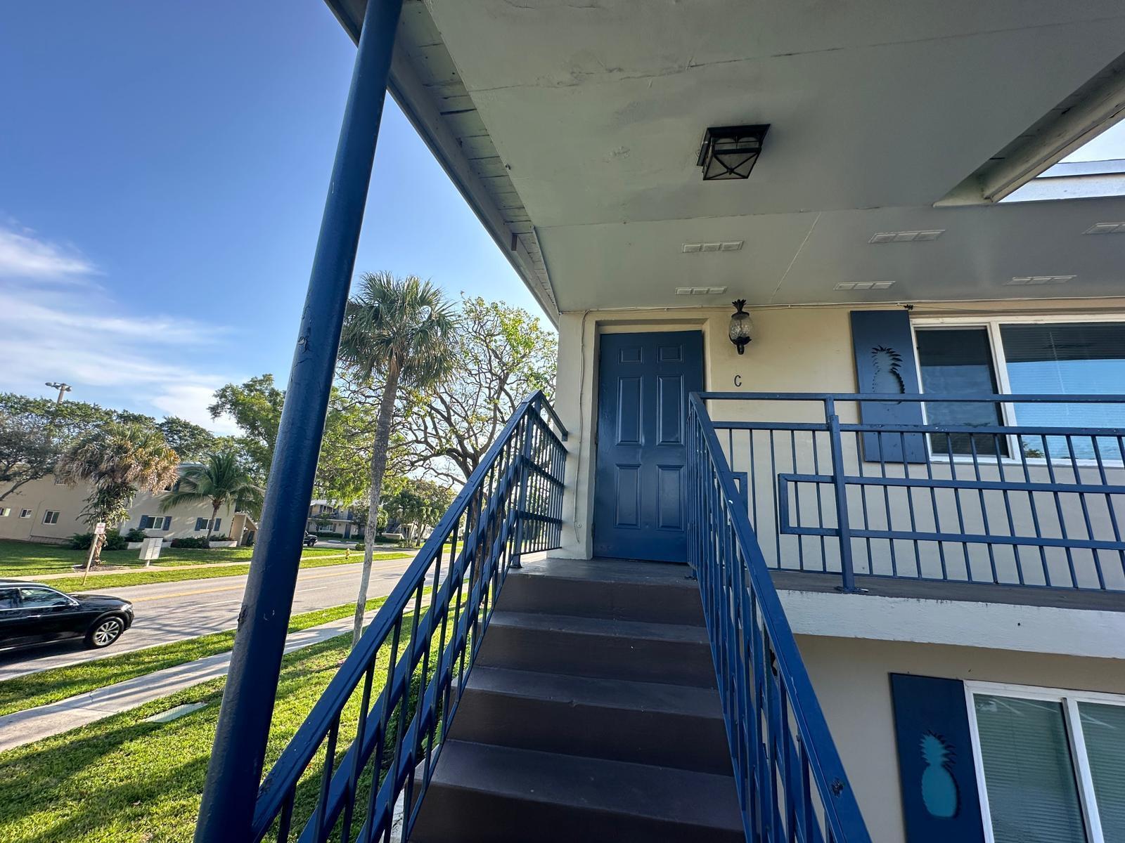 An exterior view of a blue staircase leading to a second-story apartment entrance — 817 Lighthouse Drive # C, North Palm Beach FL 33408, NORTH PALM BEACH, FL