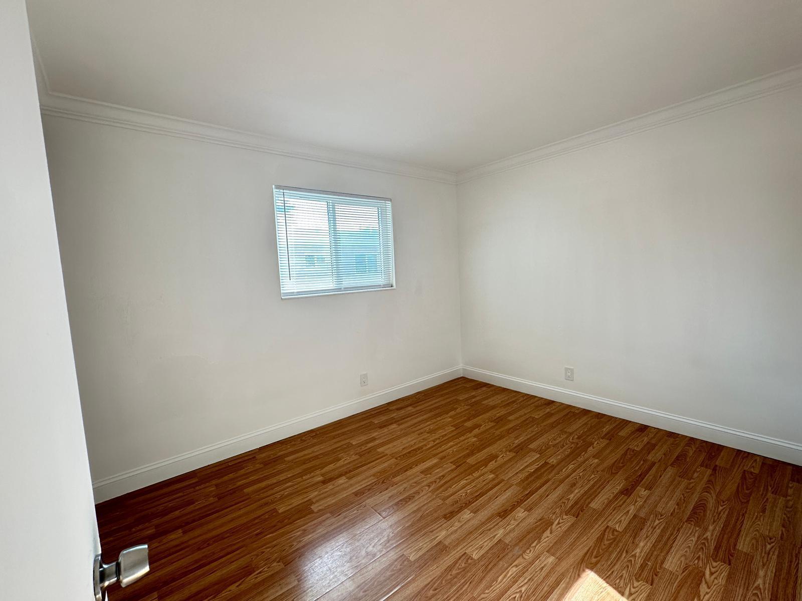 An empty room with white walls, crown molding, and wood-look laminate flooring — 817 Lighthouse Drive # C, North Palm Beach FL 33408, NORTH PALM BEACH, FL