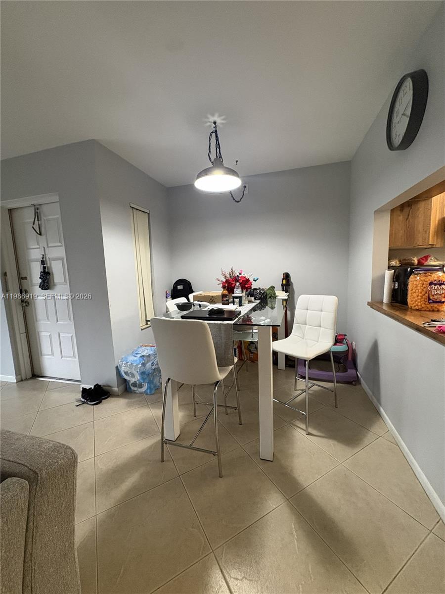 A dining area features a glass-topped table, white chairs, tile flooring, and a pendant light — 718 Sunny Pine Way # D1, Green Acres FL 33415, GREEN ACRES, FL