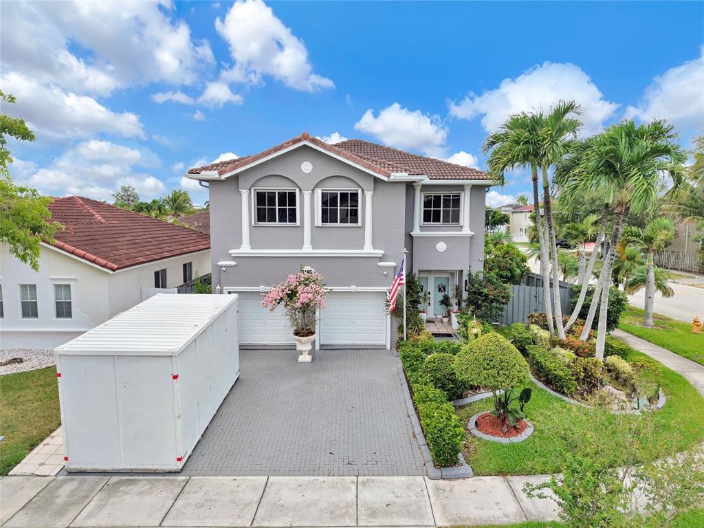 A two-story gray house with a tiled roof, a paved driveway, and a large storage container — 14402 SW 157TH PATH, MIAMI, FL