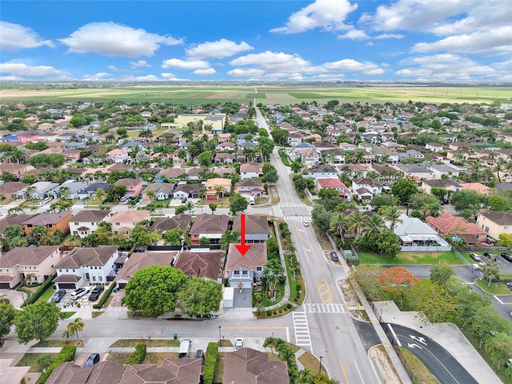 An aerial view shows a residential house with a red arrow pointing to its roof — 14402 SW 157TH PATH, MIAMI, FL