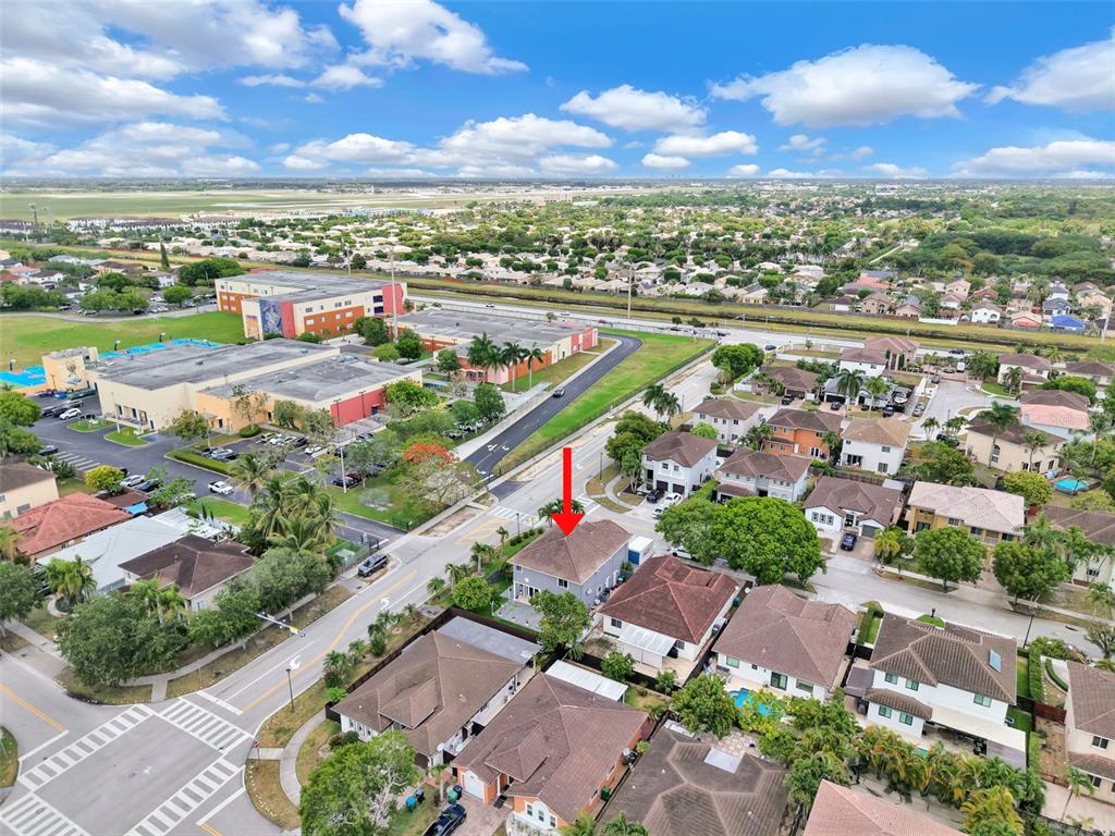 An aerial view shows a residential neighborhood with a red arrow pointing to a house — 14402 SW 157TH PATH, MIAMI, FL