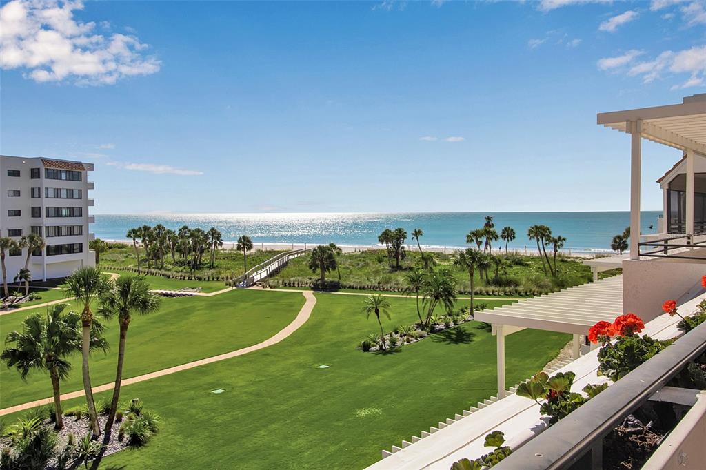 An elevated view of a grassy lawn, palm trees, a beach walkway, and the ocean — 1485 GULF OF MEXICO DRIVE UNIT 303, LONGBOAT KEY, FL
