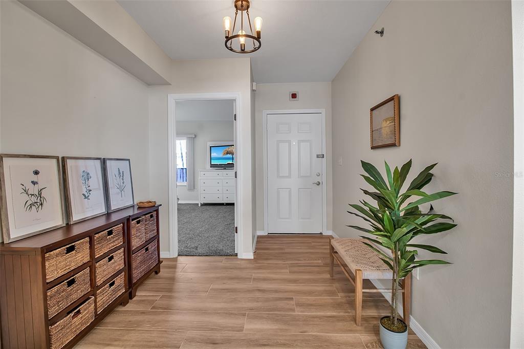 An entryway features wood-look tile flooring, a storage console with baskets, and a potted plant — 1485 GULF OF MEXICO DRIVE UNIT 303, LONGBOAT KEY, FL