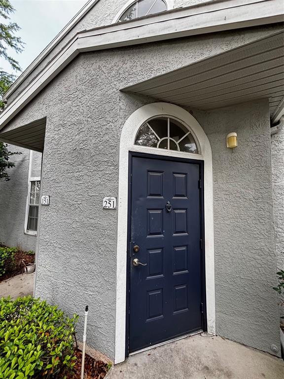 A dark blue front door with a transom window sits on a gray stucco exterior — 1615 COLUMBIA ARMS CIRCLE UNIT 251, KISSIMMEE, FL