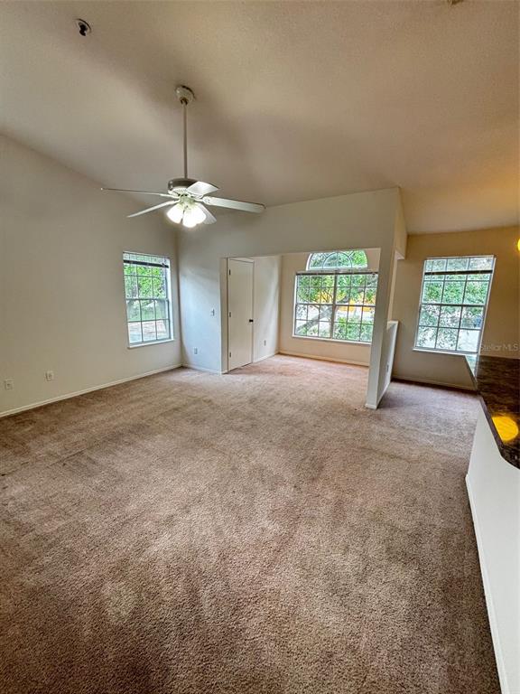 A carpeted living room features a ceiling fan, vaulted ceilings, and multiple windows — 1615 COLUMBIA ARMS CIRCLE UNIT 251, KISSIMMEE, FL