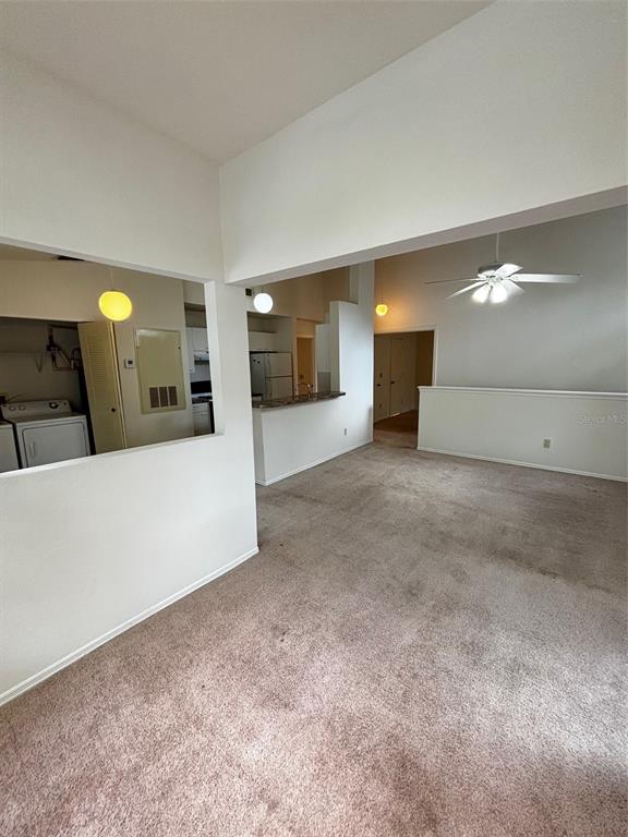 An interior view shows a carpeted living area, a kitchen with a breakfast bar, and laundry — 1615 COLUMBIA ARMS CIRCLE UNIT 251, KISSIMMEE, FL