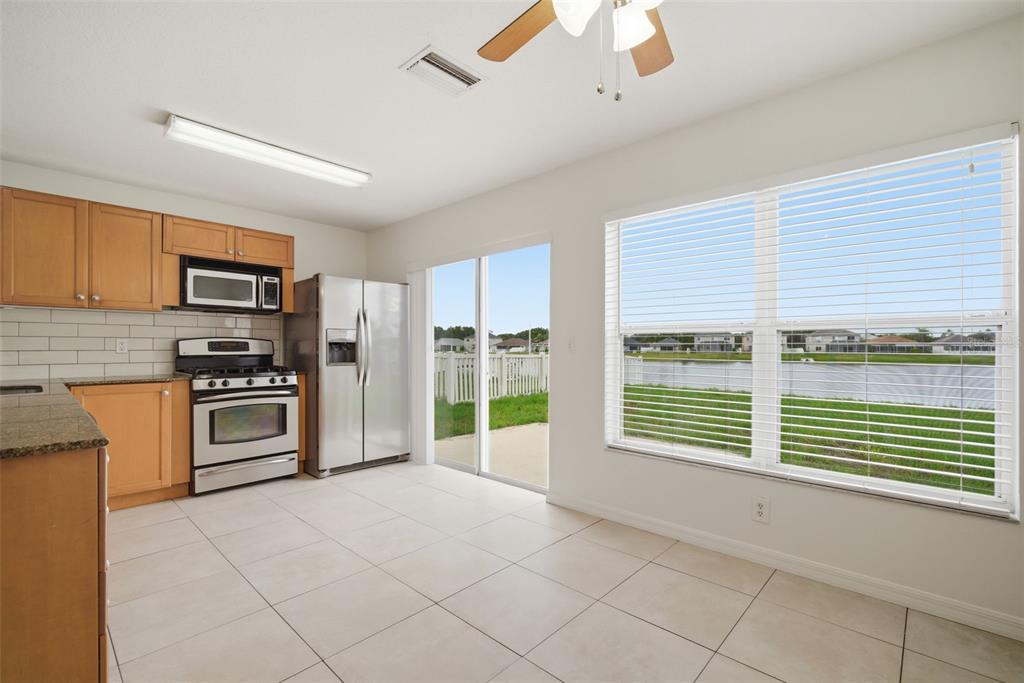 A kitchen with light wood cabinets, stainless steel appliances, tile floors, and a water view — 10604 LAKESIDE VISTA DRIVE, RIVERVIEW, FL