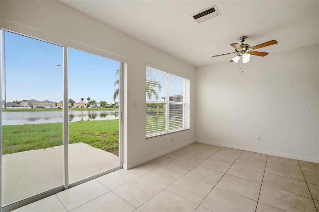 An empty room with light tile floors, a ceiling fan, and sliding doors to a lake — 10604 LAKESIDE VISTA DRIVE, RIVERVIEW, FL