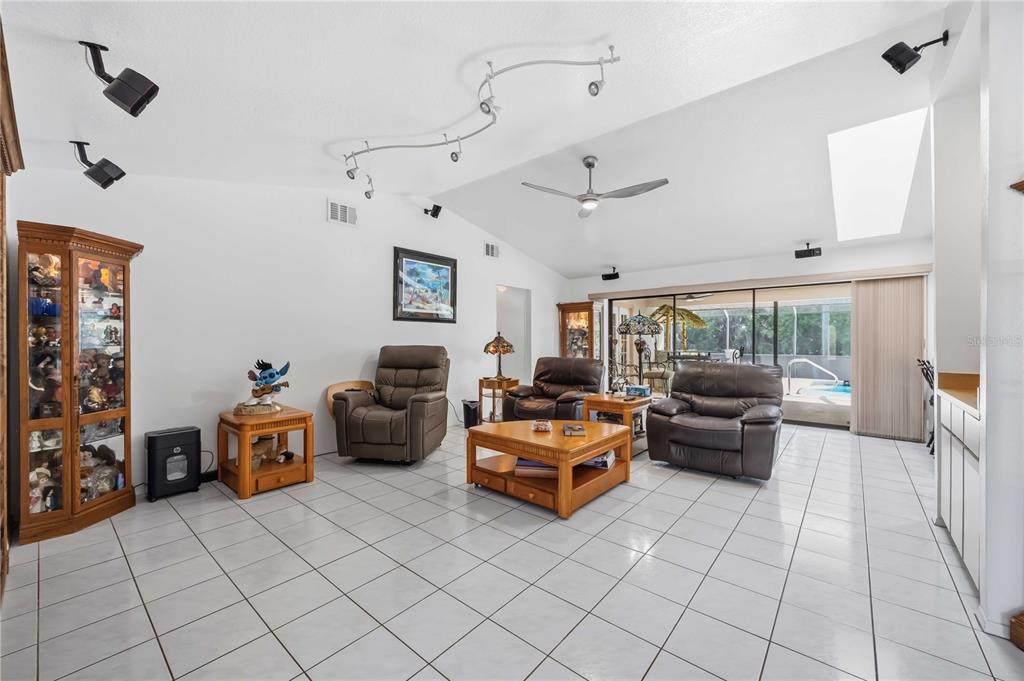 A living room with white tile floors, brown leather recliners, and a vaulted ceiling — 4346 MELIS STREET, PORT CHARLOTTE, FL