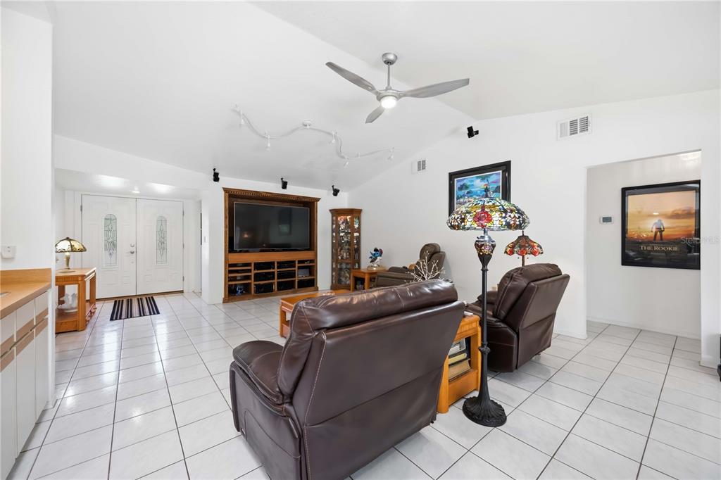 A living room features white tile floors, a vaulted ceiling, leather recliners, and a media center — 4346 MELIS STREET, PORT CHARLOTTE, FL