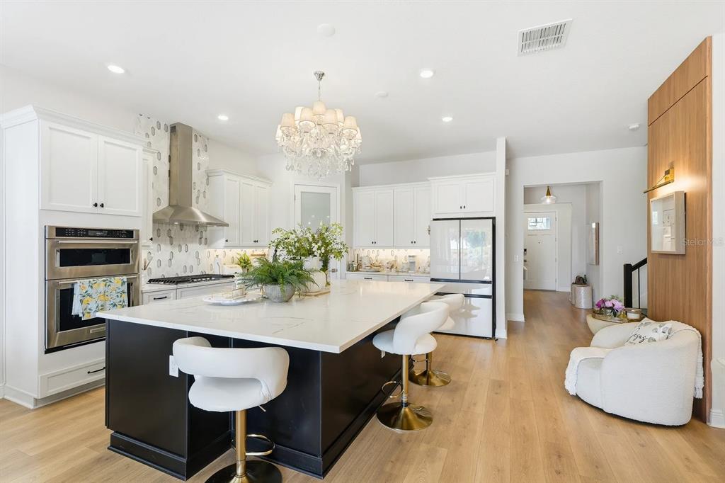A modern kitchen features a black island with white countertops, white cabinetry, and wood flooring — 16312 VOLTERRA POINT, BELLA COLLINA, FL