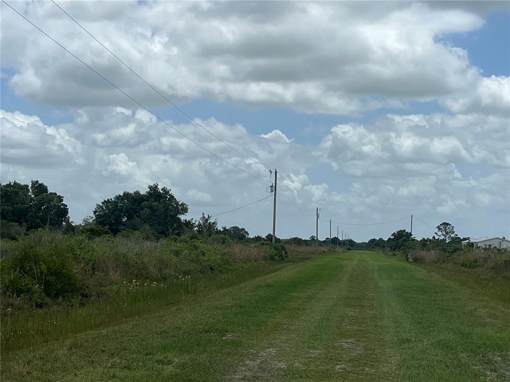 A grassy path leads through an open, undeveloped field under a cloudy sky — 19092 NW 250TH STREET, OKEECHOBEE, FL