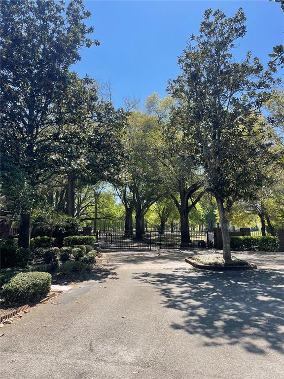 A paved driveway leads to a gated entrance surrounded by large, mature trees — 7652 SPRING BAY COVE UNIT 3, ORLANDO, FL