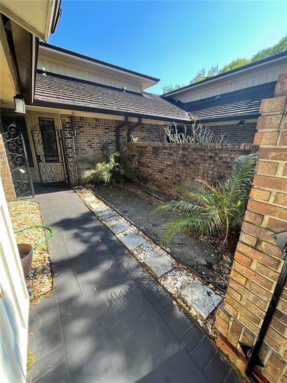A brick-walled courtyard features a dark paved walkway, stone accents, and small palm plants — 7652 SPRING BAY COVE UNIT 3, ORLANDO, FL