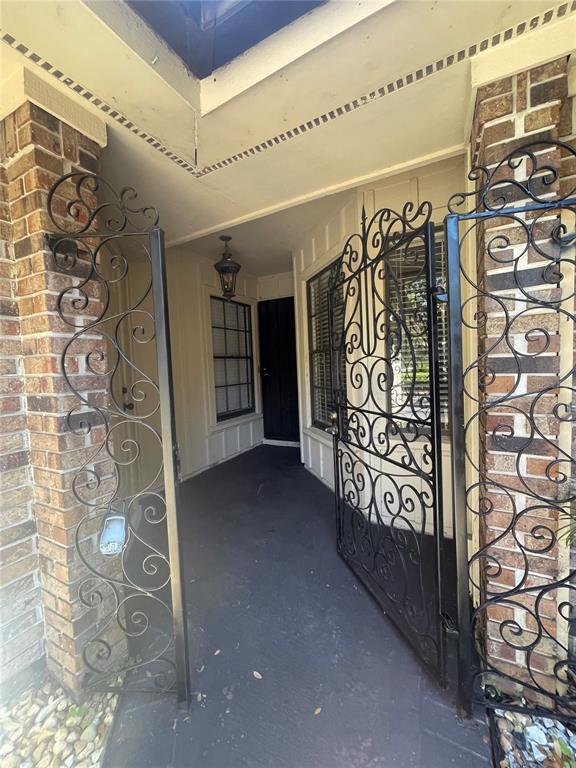 A covered entryway features a dark floor, brick pillars, and decorative black metal security gates — 7652 SPRING BAY COVE UNIT 3, ORLANDO, FL
