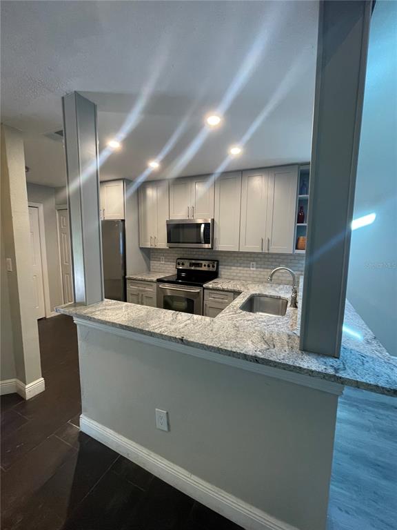 A kitchen features light gray cabinets, granite countertops, stainless steel appliances, and a breakfast bar — 7652 SPRING BAY COVE UNIT 3, ORLANDO, FL