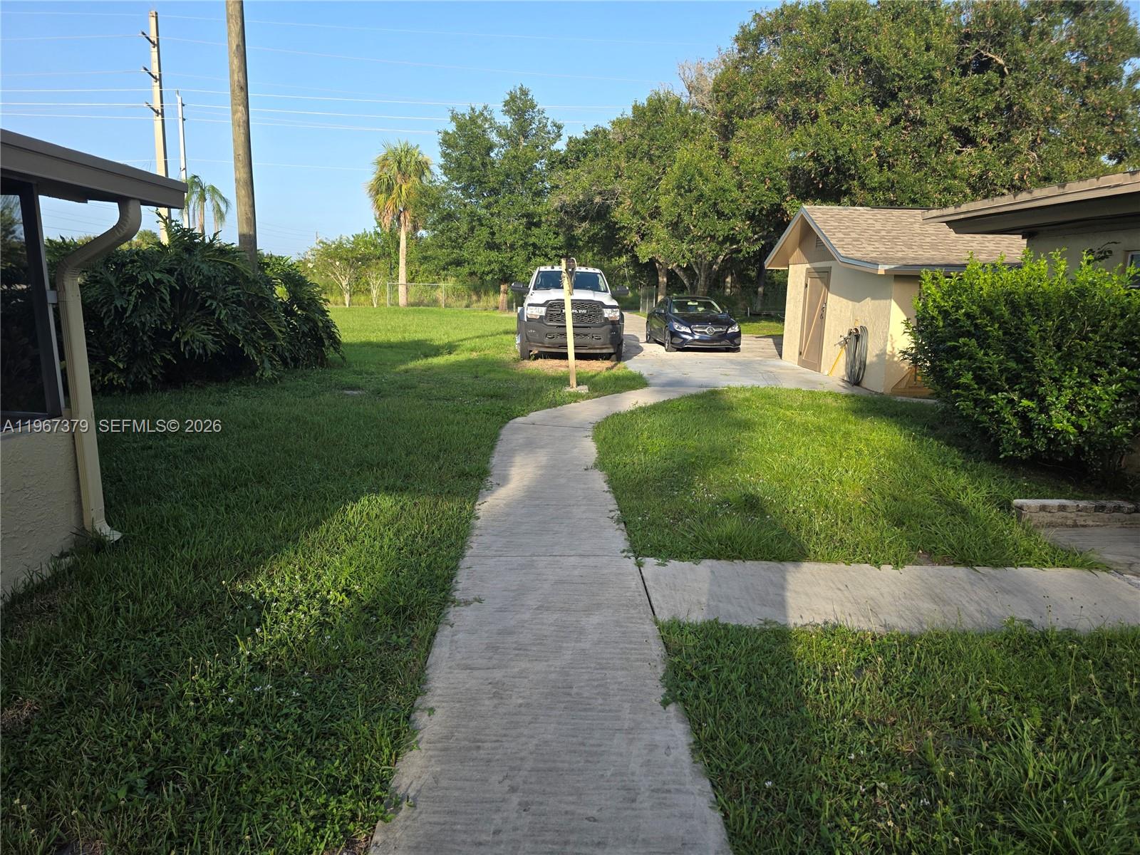 A concrete walkway leads past a house and garage toward two parked vehicles — 4321 Kirby Loop Rd # 2, Fort Pierce FL 34981, FORT PIERCE, FL