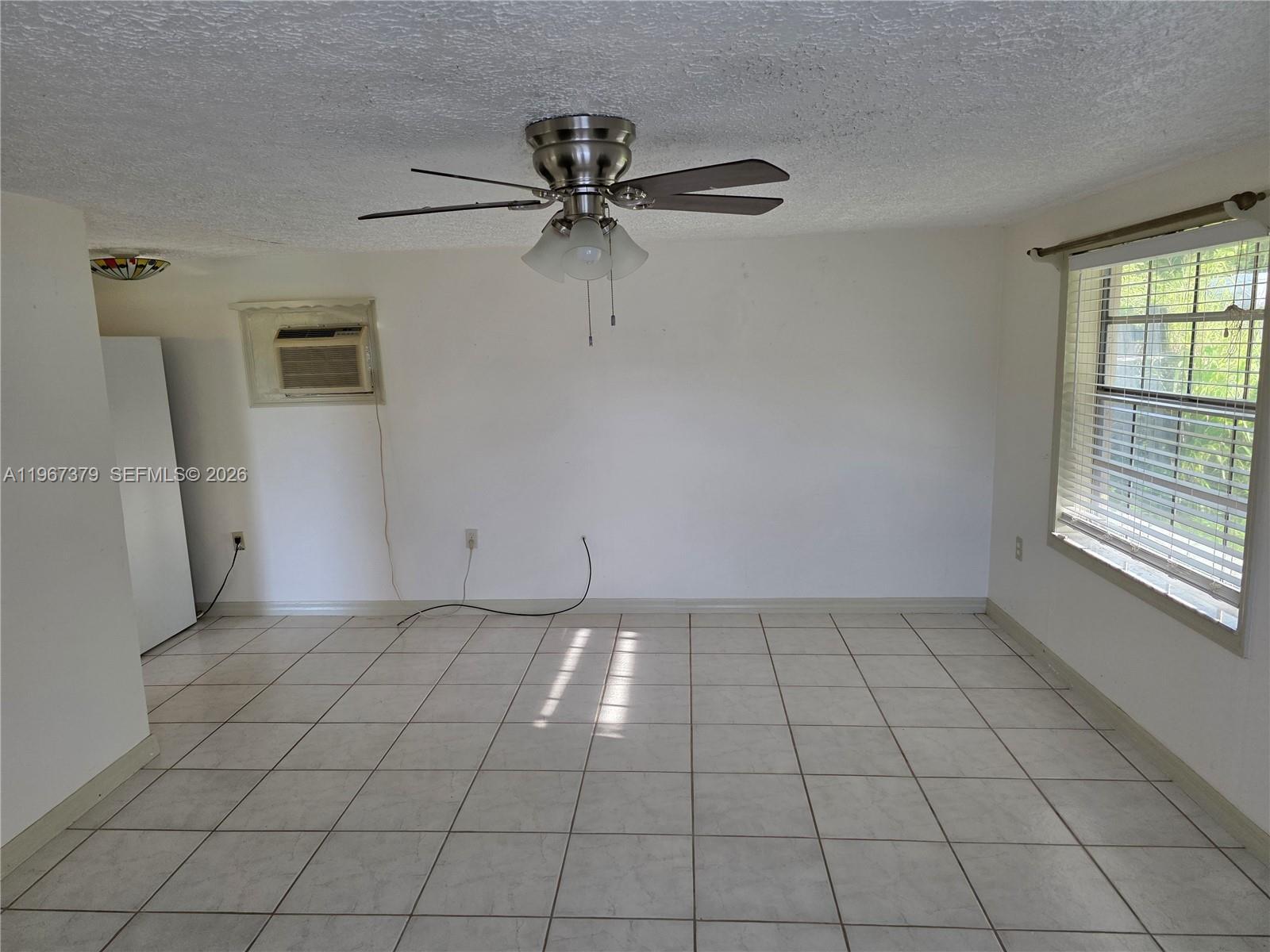 An empty room features white walls, tiled flooring, a ceiling fan, and a window — 4321 Kirby Loop Rd # 2, Fort Pierce FL 34981, FORT PIERCE, FL