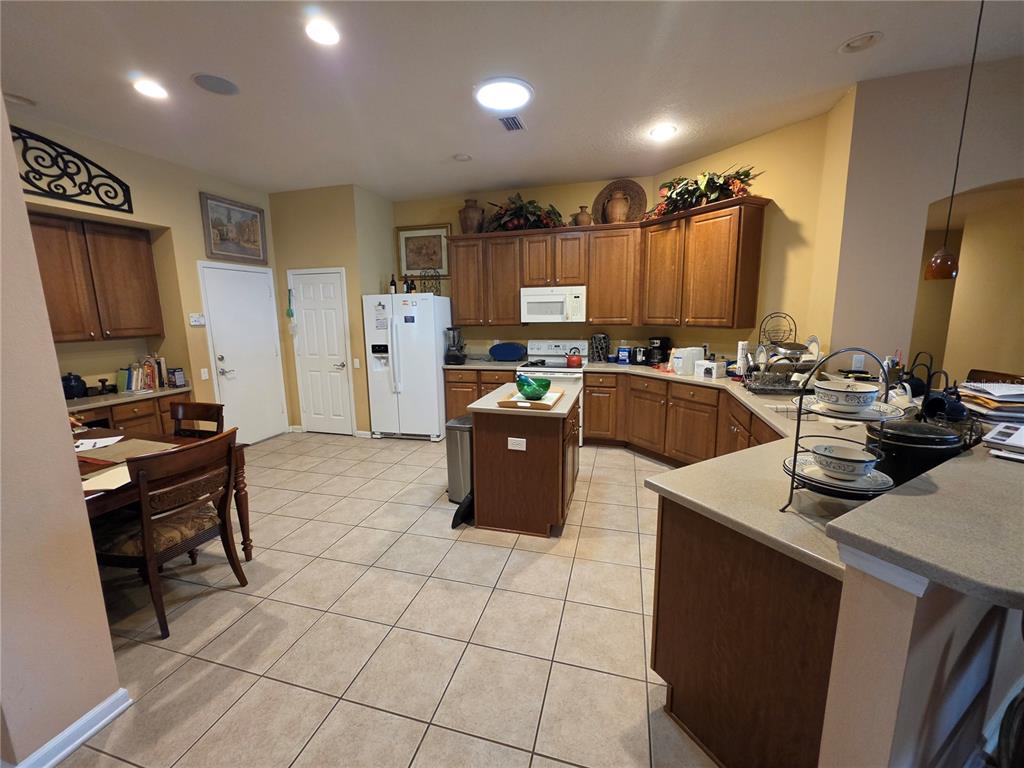 A kitchen with wood cabinets, tile flooring, a central island, and a dining area — 3608 JUNEBERRY DRIVE, WESLEY CHAPEL, FL