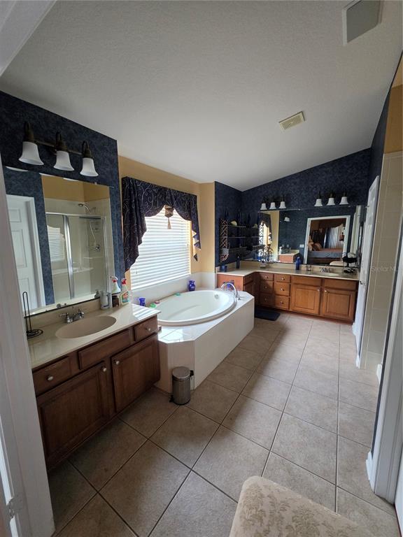 A primary bathroom features dual wood vanities, a central soaking tub, and dark blue wallpaper — 3608 JUNEBERRY DRIVE, WESLEY CHAPEL, FL