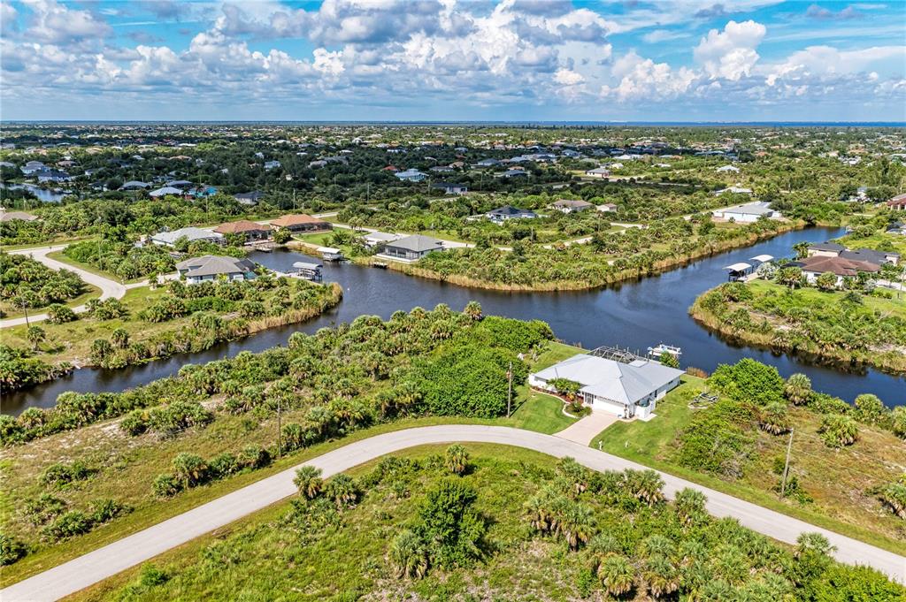 An aerial view shows a house with a pool cage situated at a canal intersection — 10442 MCALESTER CIRCLE, PORT CHARLOTTE, FL
