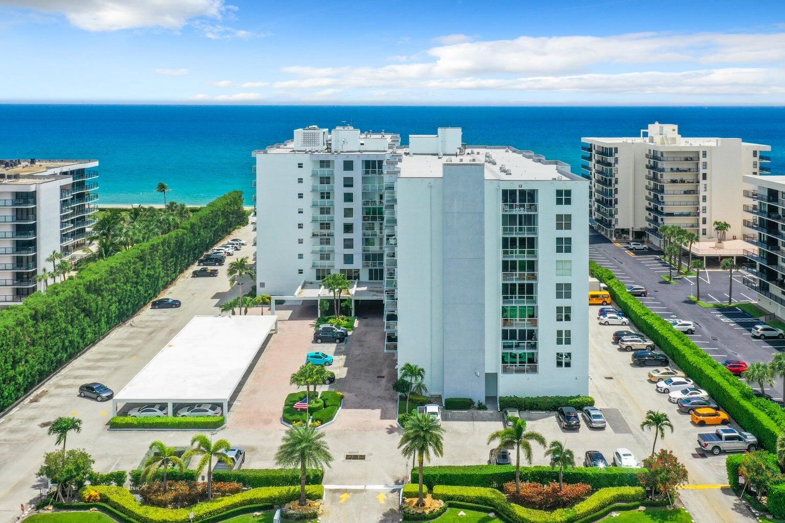 An aerial view shows a white multi-story apartment building with parking lots near the ocean — 3450 S Ocean Boulevard # 102, Palm Beach FL 33480, PALM BEACH, FL