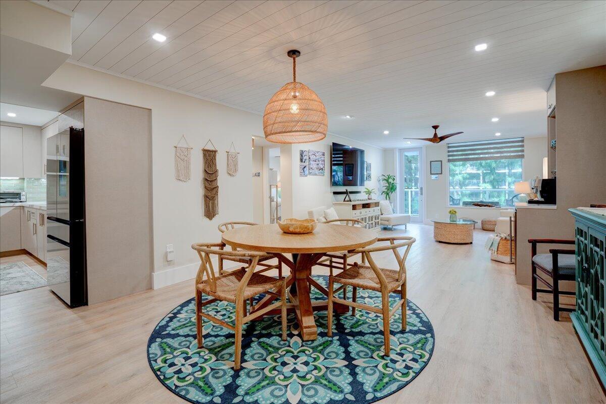 A dining area with a round wooden table and woven chairs sits before a living room — 3450 S Ocean Boulevard # 102, Palm Beach FL 33480, PALM BEACH, FL