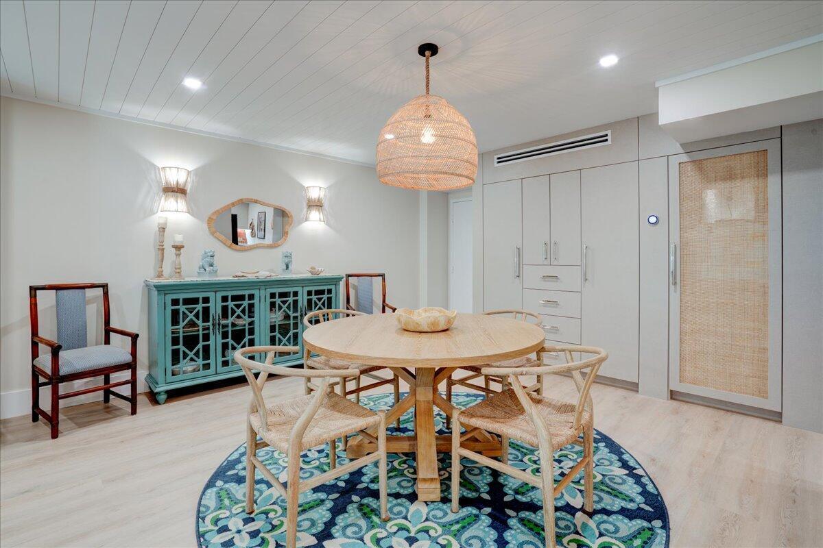 A dining room features a round wooden table, woven chairs, and a blue patterned rug — 3450 S Ocean Boulevard # 102, Palm Beach FL 33480, PALM BEACH, FL