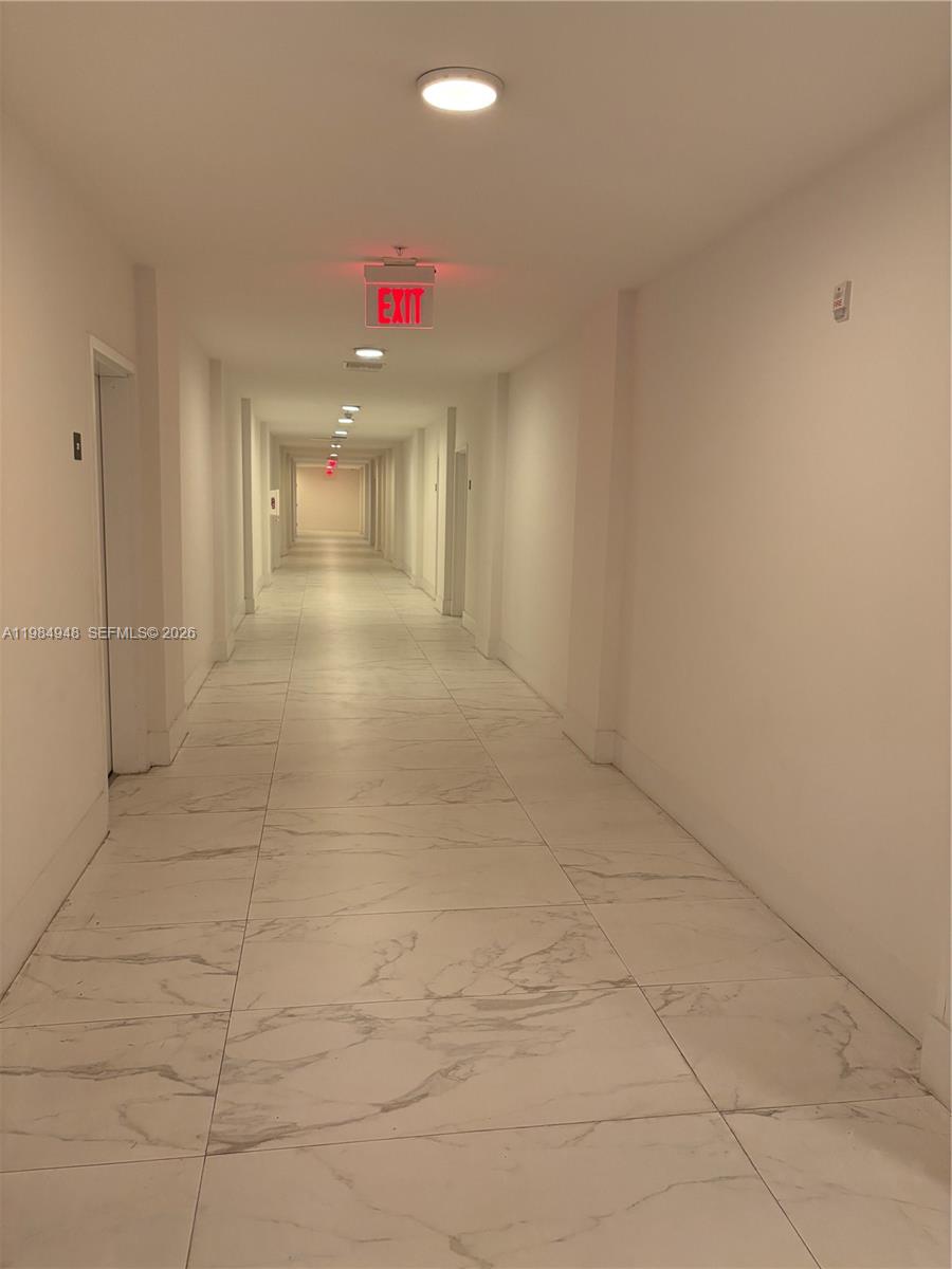 A long, narrow hallway features white walls, marble-patterned tile flooring, and recessed ceiling lighting — 10950 NW 82nd St # 319, Doral FL 33178, DORAL, FL