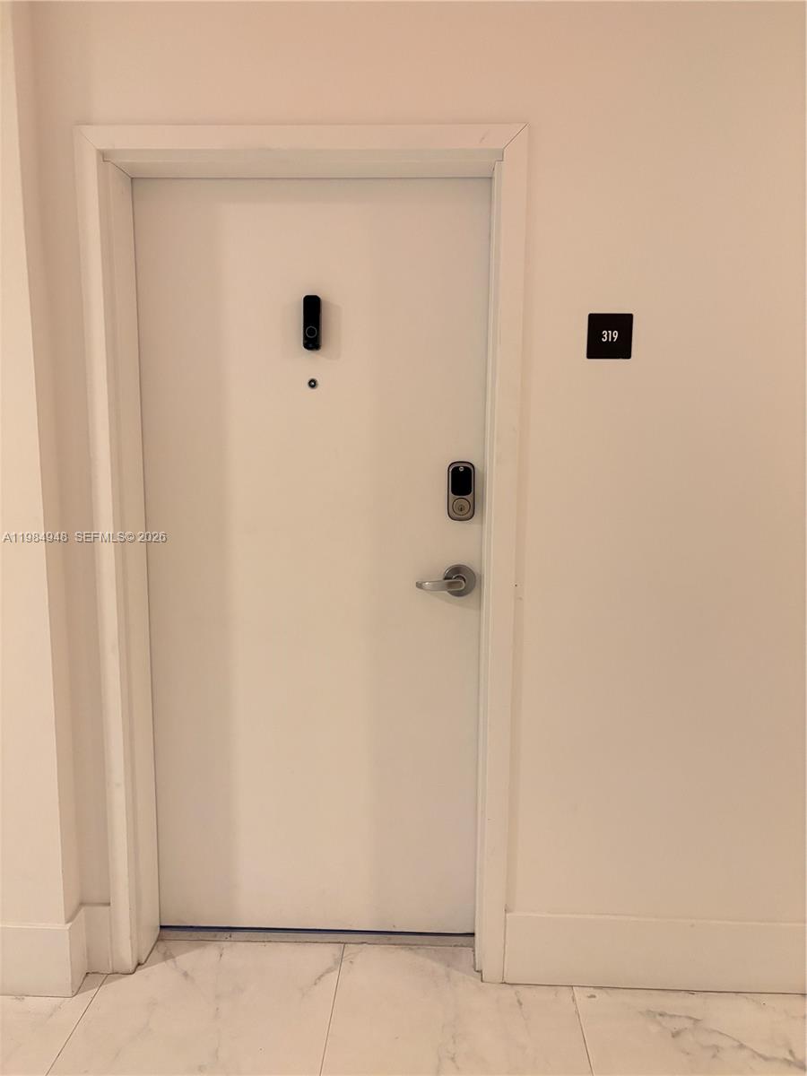 A white door with a smart lock and a room number sign sits in a hallway — 10950 NW 82nd St # 319, Doral FL 33178, DORAL, FL