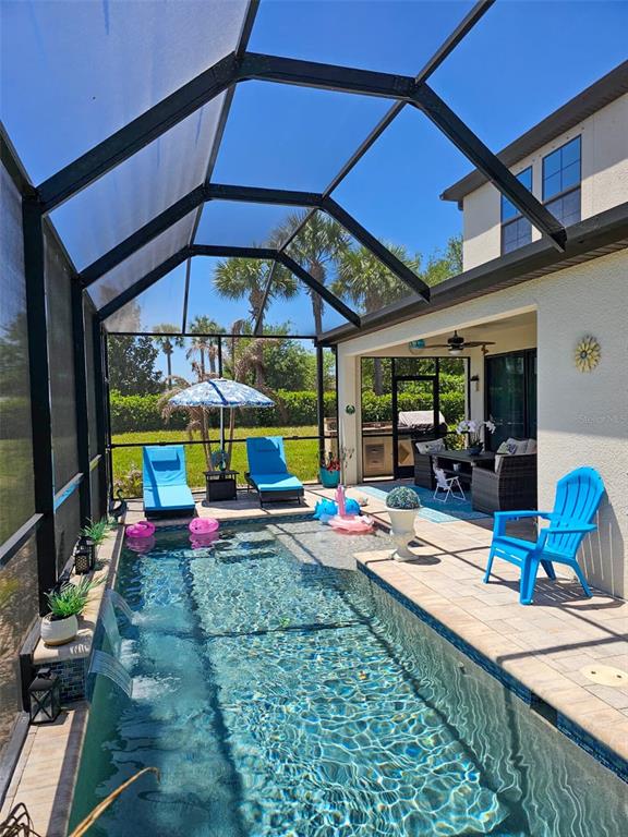 A screened-in patio features a rectangular swimming pool, lounge chairs, and an outdoor dining area — 12860 SATIN LILY DRIVE, RIVERVIEW, FL