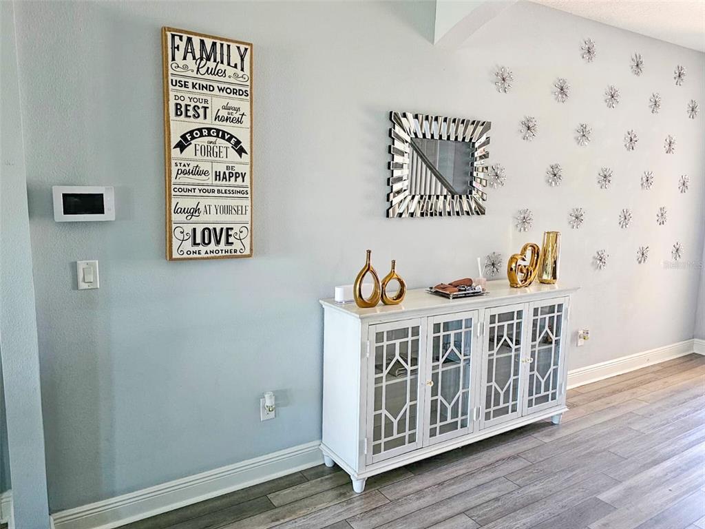 A white cabinet with glass doors sits against a light blue wall with wall decor — 12860 SATIN LILY DRIVE, RIVERVIEW, FL