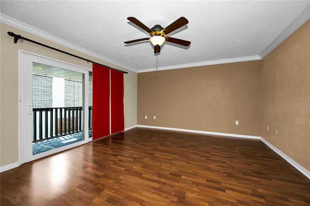 An empty room with wood-look flooring, a ceiling fan, and a sliding glass door — 743 HAVEN PLACE UNIT 743, TARPON SPRINGS, FL