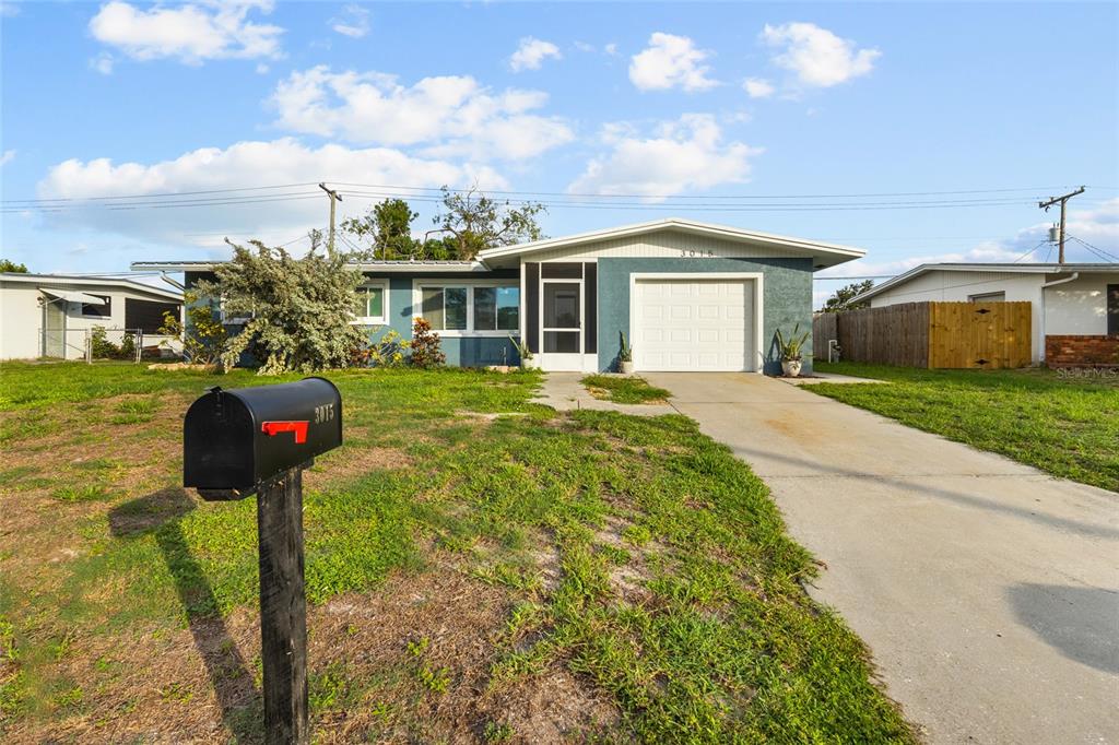 A single-story house with a blue exterior, a white garage door, and a front lawn — 3015 SOUTHERN PARKWAY W, BRADENTON, FL