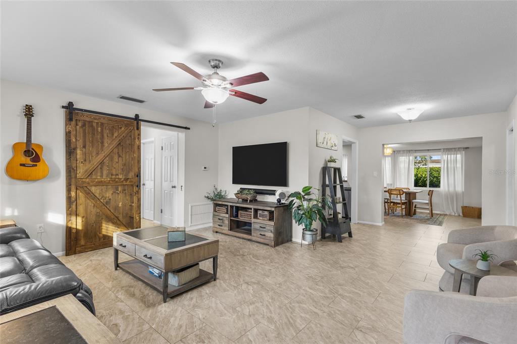 A living room with tile flooring, a barn door, a ceiling fan, and a television — 3015 SOUTHERN PARKWAY W, BRADENTON, FL